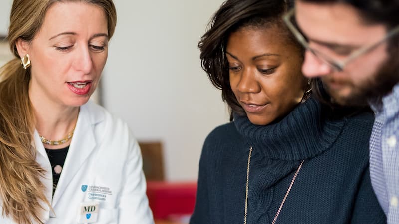 A woman doctor talking to black woman and white man